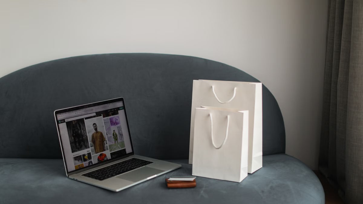 Online shopping setup with a laptop and shopping bags on a stylish couch.